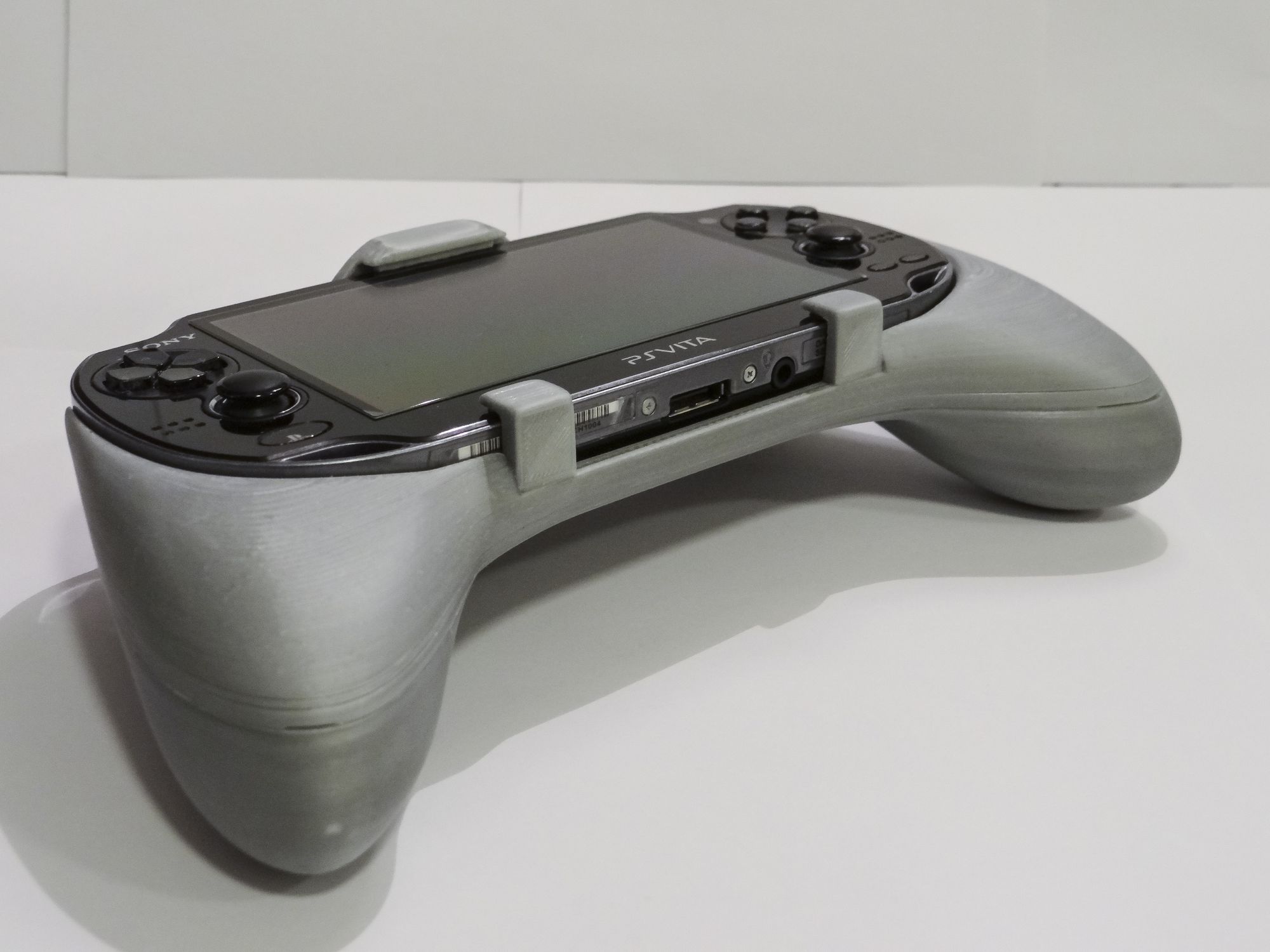 A grey gaming controller with a screen

Description automatically generated